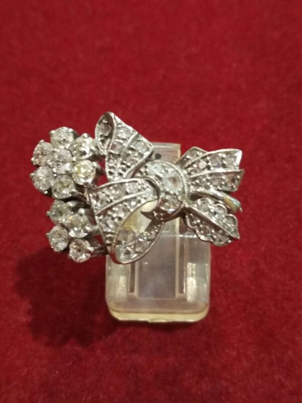 Sortija con motivos florales y lazada en platino y diamantes. 1950-1960.